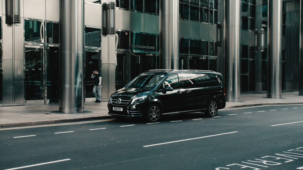 Black luxury sedan parked on sidewalk for private transfer service