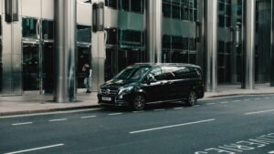 Black luxury sedan parked on sidewalk for private transfer service